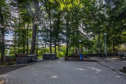 a park with benches and tables and trees at 4 Évszak Hegyihotel in Mátraháza
