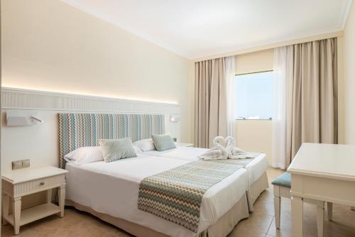 a bedroom with a large white bed and a window at Can Picafort Palace in Can Picafort