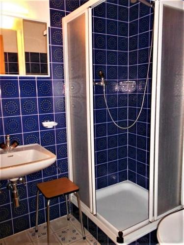a blue tiled bathroom with a shower and a sink at Combyre C 024 -COMFORTABLE apartment 4 pers in Veysonnaz
