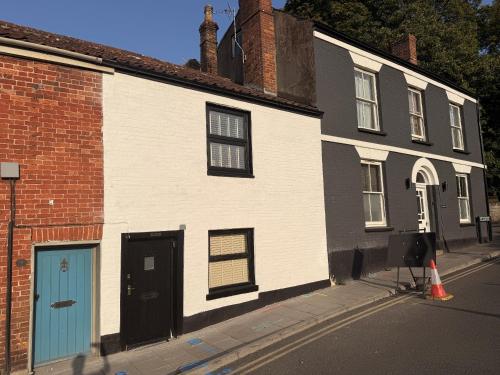 a white building with a blue door on a street at Globe Cottage in Glastonbury