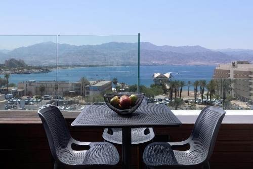 a table with chairs and a bowl of fruit on a balcony at Luxury Apartments And Studios At Sea Side By Rently in Eilat