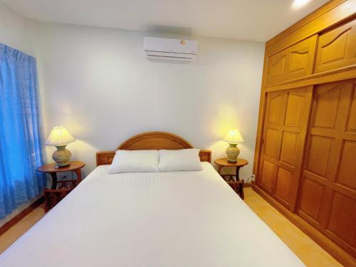 a bedroom with a bed with two lamps on two tables at The Rinra Kamala Hut in Kamala Beach