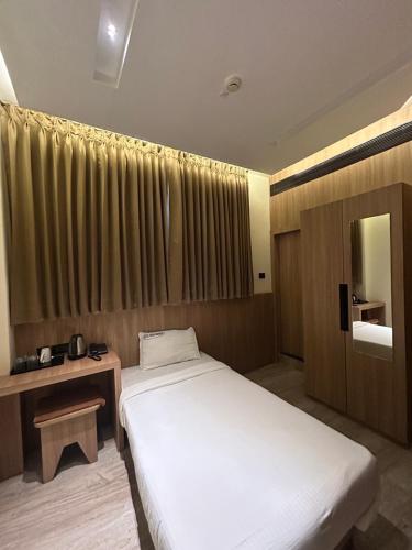 a bedroom with a large white bed and a window at Hotel Indian Imperial in Kumbakonam