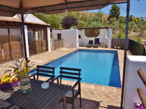 Una villa con piscina, mesa y sillas. en Countryside Villa Escape, en La Joya