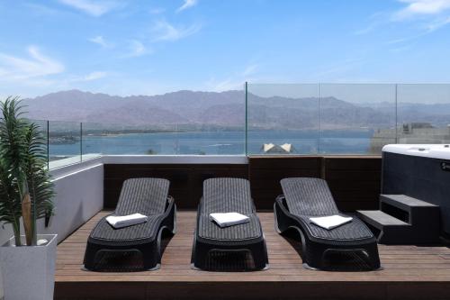 a balcony with chairs and a view of the mountains at Luxury Apartments And Studios At Sea Side By Rently in Eilat
