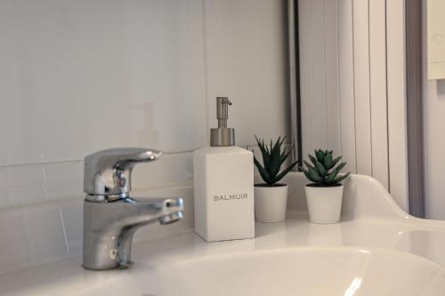 a bathroom sink with a soap bottle next to a mirror at Santa's City Suite by Book Lapland in Rovaniemi