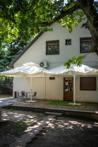 two white umbrellas in front of a house at 4 Évszak Völgyhotel in Mátrafüred