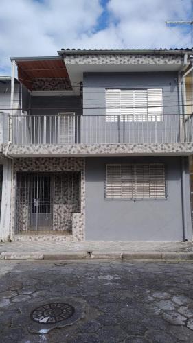 une maison blanche avec un balcon et une rue dans l'établissement Casa Praia Mongagua - Cantinho Familia pé na Areia, à Mongaguá