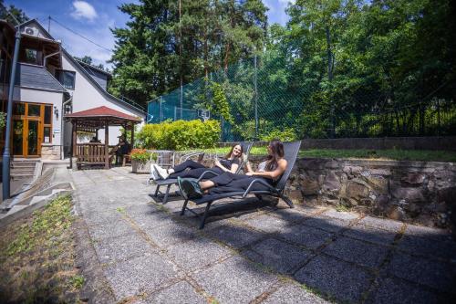two women sitting on a bench in a yard at 4 Évszak Völgyhotel in Mátrafüred