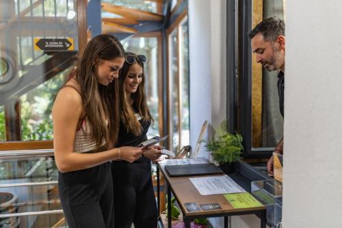 two women standing next to a man looking at a cell phone at 4 Évszak Völgyhotel in Mátrafüred