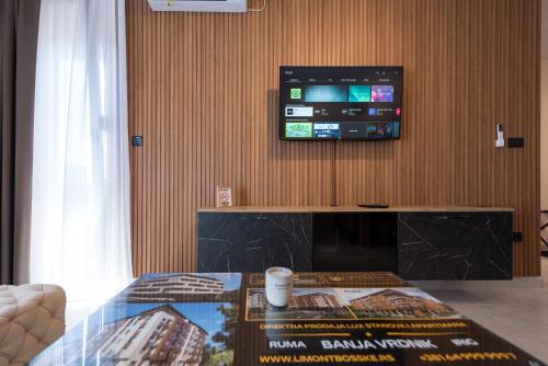 a living room with a table and a tv on a wall at Crystal Luxury Apartments in Vrdnik