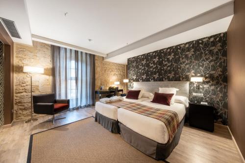 a hotel room with a bed and a chair at Castilla Termal Burgo de Osma in El Burgo de Osma