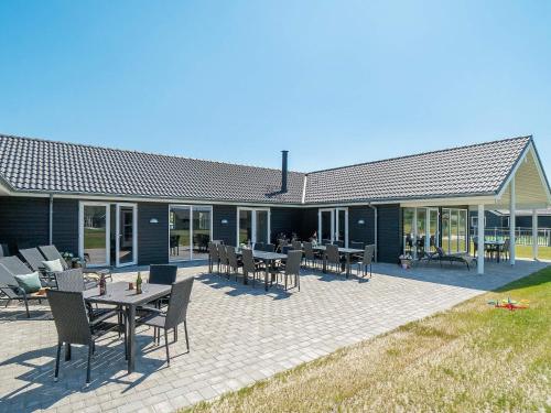 30 person holiday home in Nørre Nebel في Nørre Nebel: فناء فيه طاولات وكراسي امام مبنى