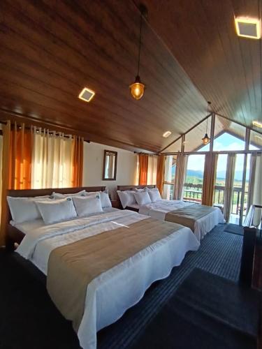 a large bedroom with two beds and a large window at Prime England Cottages in Nuwara Eliya