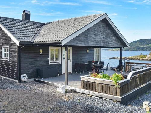 een zwart huis met een terras en een tafel bij 8 person holiday home in TORVIKBUKT in Torvikbukt