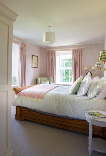 a bedroom with a large bed with pink curtains at East Lodge, Bughtrig in Coldstream