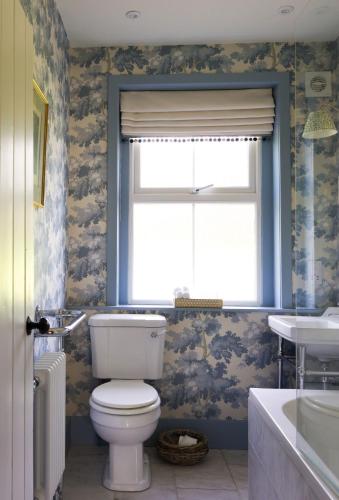 a bathroom with a toilet and a window and a sink at East Lodge, Bughtrig in Coldstream