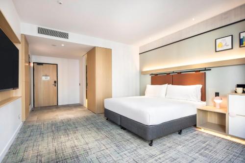 a hotel room with a bed and a flat screen tv at Holiday Inn Melbourne Bourke Street Mall by IHG in Melbourne