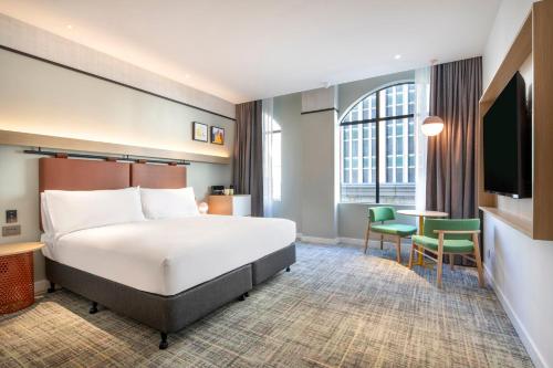 a hotel room with a bed and a table and chairs at Holiday Inn Melbourne Bourke Street Mall by IHG in Melbourne
