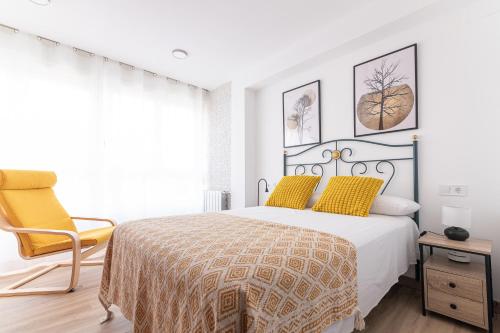 a white bedroom with a bed and a chair at Amplio y reformado apartamento centro Santander in Santander