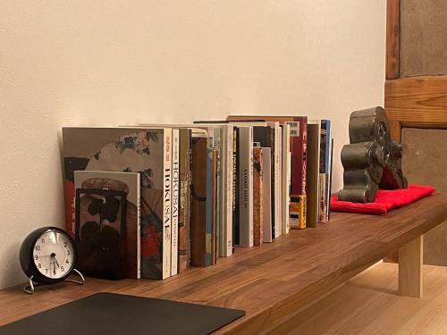 a row of books on a shelf with a clock at Deguchiya in Fujikawa