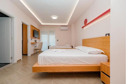 a bedroom with a large white bed and a desk at Paloka Collection Hotel in Shëngjin