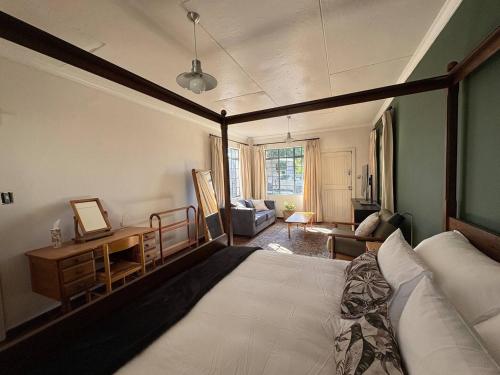 ein Schlafzimmer mit einem großen Bett und einem Schreibtisch in der Unterkunft Oatlands Cottages in Grahamstown