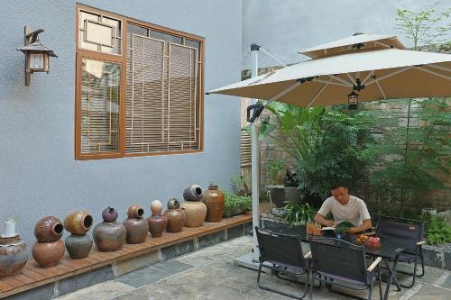 a man sitting at a table under an umbrella at 凤凰古城树喜民宿店Shuxi Guesthouse- Fenghuang Ancient Town in Fenghuang