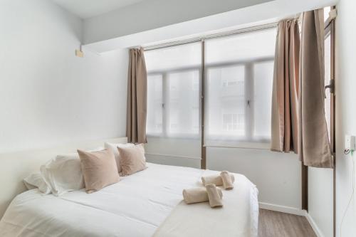 ein Schlafzimmer mit einem weißen Bett mit einem großen Fenster in der Unterkunft Siempreviva Beach Las Canteras in Las Palmas de Gran Canaria