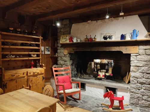 a living room with a stone fireplace with a red chair at Hotel Alla Posta in Saint Vincent