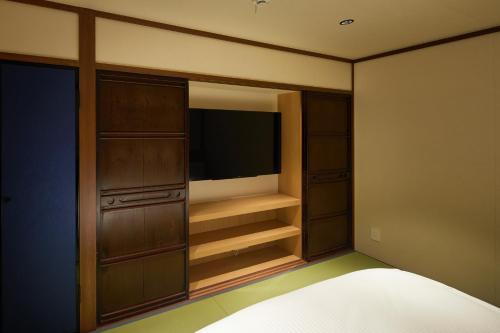 a bedroom with a tv and a bed in it at Enso Machiya in Kyoto