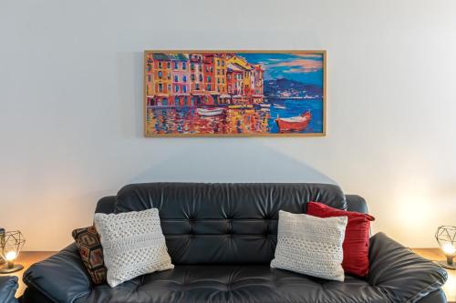 a black leather couch in a living room with a painting at Casas no Tatuapé Garagem e Portão Automático 284 a 314 in Sao Paulo