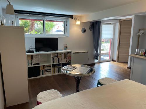 a living room with a table and a tv at La Maison Rouge in Trouville-sur-Mer