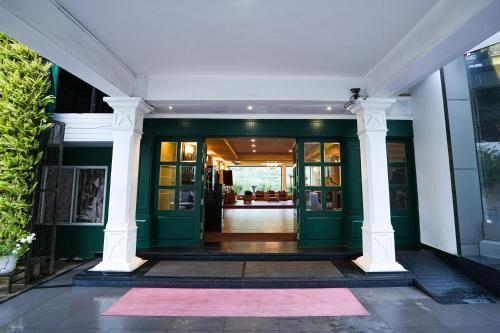 an entrance to a building with green doors and columns at Hotel C7 Munnar in Munnar