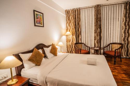 a bedroom with a large bed with two lamps and chairs at Hotel C7 Munnar in Munnar