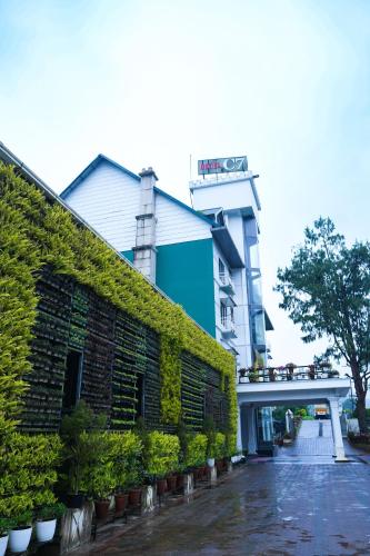 a building with a green ivy wall next to a building at Hotel C7 Munnar in Munnar