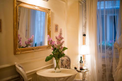 a vase of flowers on a table with a mirror at Villa Segalla in Rovinj