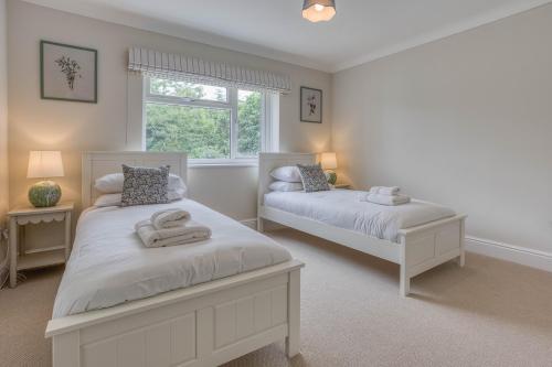 a bedroom with two beds and a window at Blackbird Cottage, Burnham Market Stylish & Chic - Crabpot Cottages, Hunstanton in Burnham Market