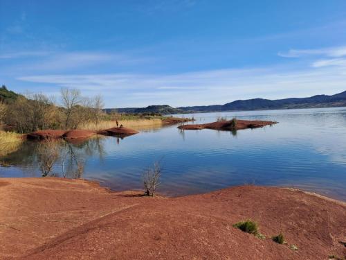 a body of water with a person standing on the shore at Le Mazet du Salagou in Clermont-lʼHérault