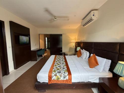 a hotel room with a large bed with orange pillows at Hotel Grand Arcasia Saket- Near PVR Anupam in New Delhi