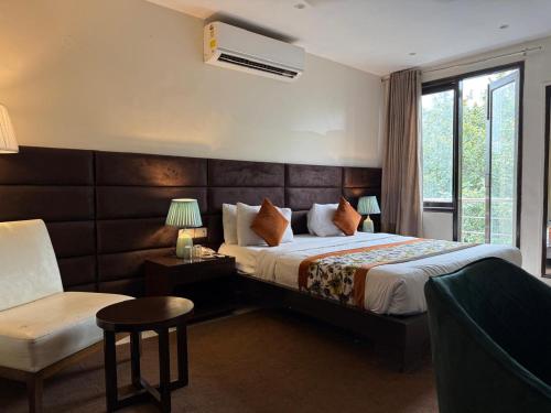 a hotel room with a bed and a chair at Hotel Grand Arcasia Saket- Near PVR Anupam in New Delhi
