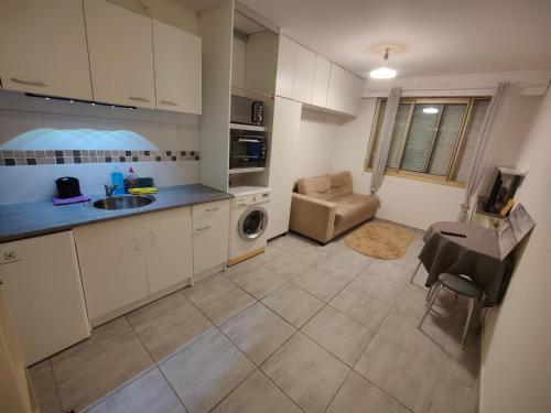 a kitchen with white cabinets and a sink and a couch at Coin paradisien à 10 MINUTES de paris in Meudon
