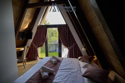 a bed in a room with a large window at Cabanele Marcus in Statjunea Borsa