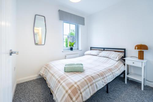 ein weißes Schlafzimmer mit einem Bett und einem Spiegel in der Unterkunft Two-bed Ground Floor Flat in Caerphilly Town Centre in Caerphilly