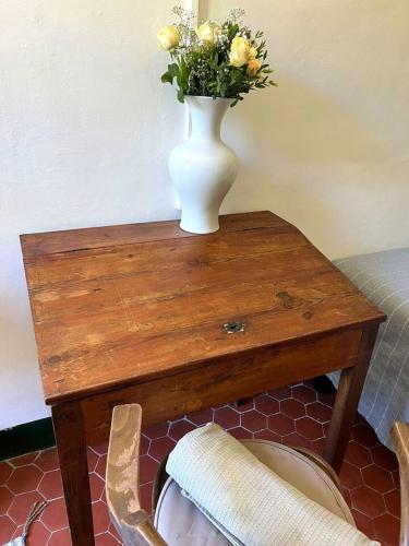 a vase with flowers on a wooden table with a chair at Villa Magdala Arts & Résidence in Hyères