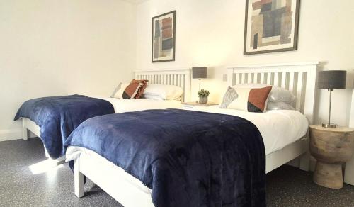 two beds in a bedroom with blue blankets on them at Simply Stay in Monaghan