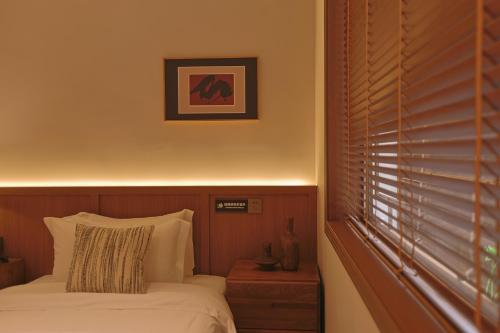 a bedroom with a bed and a window with blinds at 凤凰古城树喜民宿店Shuxi Guesthouse- Fenghuang Ancient Town in Fenghuang