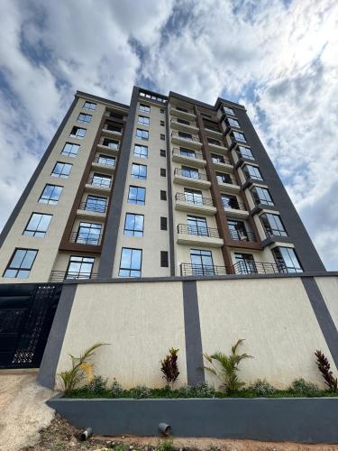 a tall apartment building with palm trees in front of it at Heri Ngong Heights 5th floor in Nairobi