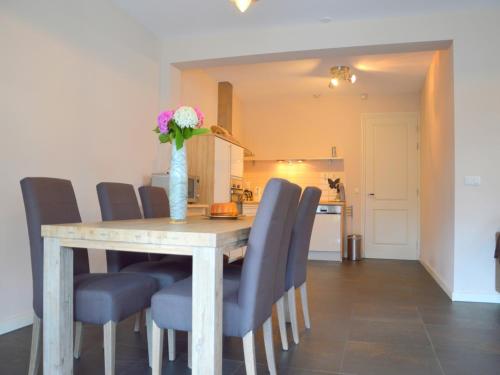 a dining room table with blue chairs and a vase with flowers at Apartment in Posterholt near Meinweg Park in Posterholt