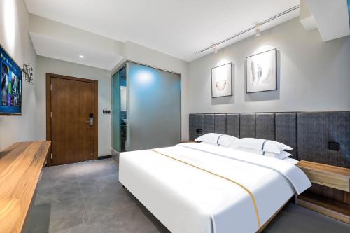 a bedroom with a large white bed and a wooden headboard at 梦境酒店壹号客栈 in Zhangjiajie